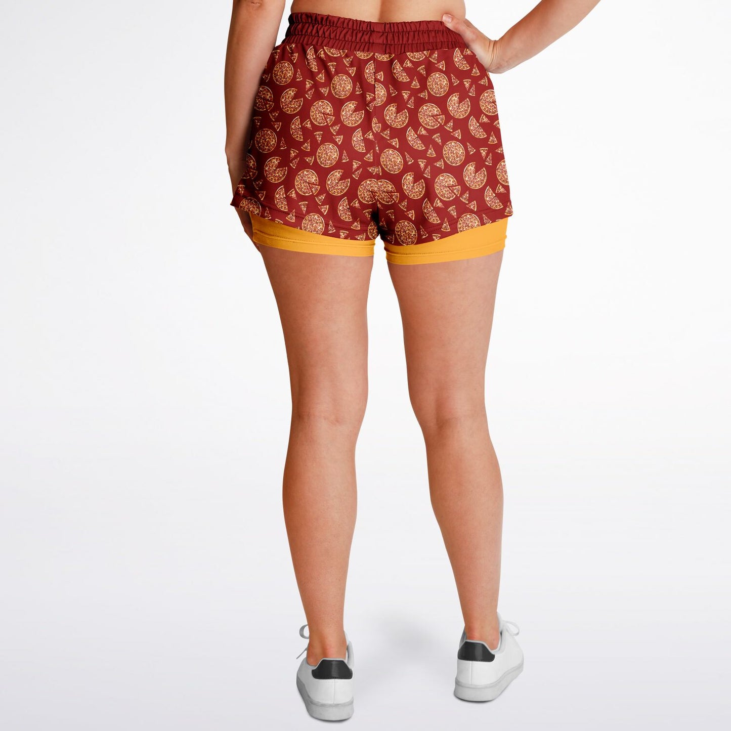 Women’s shorts featuring a pizza design of pizza pies and pizza slices on a red background with an orange under short.