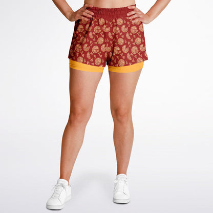 Women’s shorts featuring a pizza design of pizza pies and pizza slices on a red background with an orange under short.