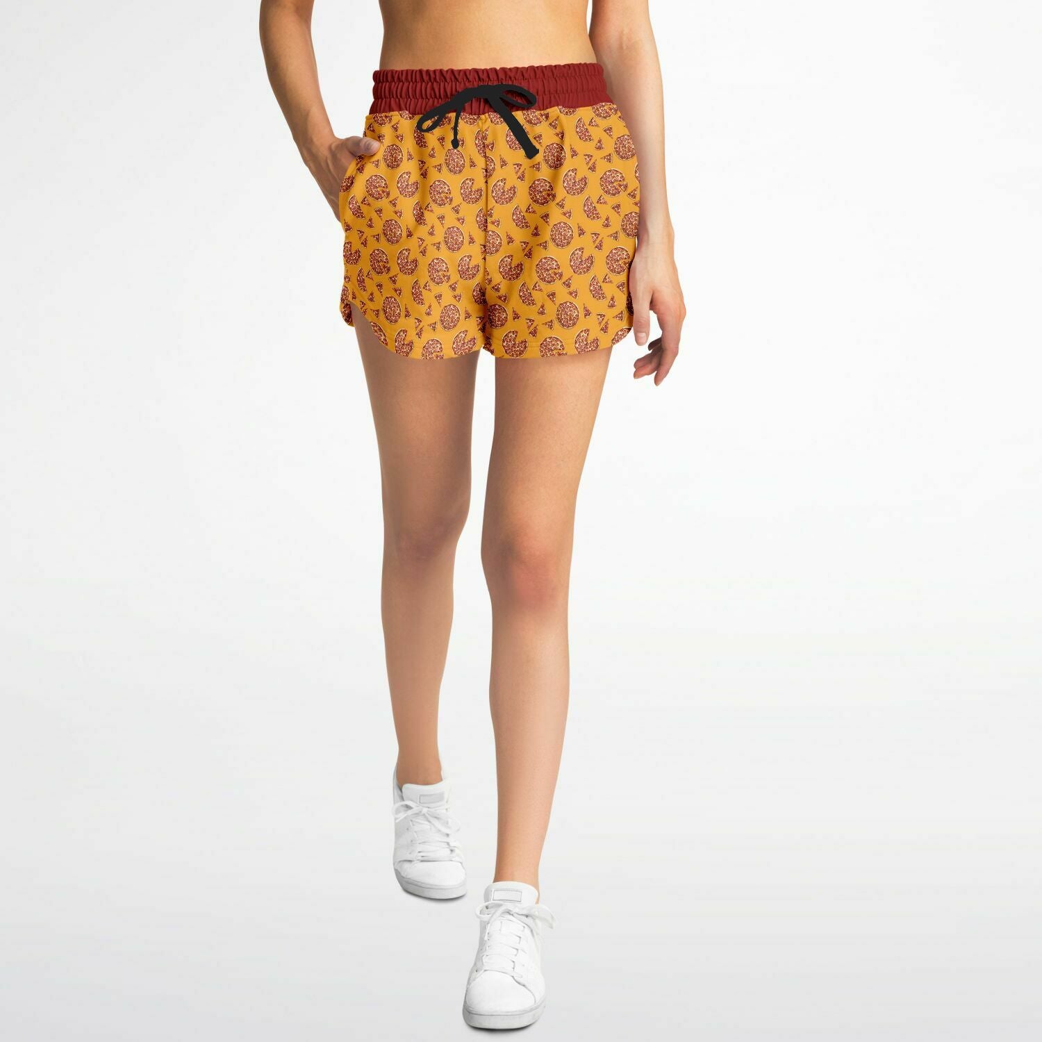 Women’s shorts featuring a pizza design of pizza pies and pizza slices on a yellow background with a red waistband and red outer pocket with a slice of pizza.