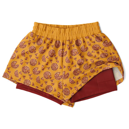 Women's shorts featuring a pizza design of pizza pies and pizza slices on a yellow background with a red undershort.