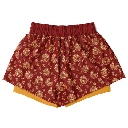 Women’s shorts featuring a pizza design of pizza pies and pizza slices on a red background with an orange under short.