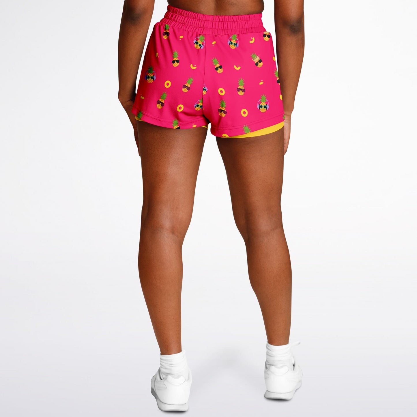 Women's 2-in-1 Shorts. These fun shorts feature a pink background with pineapples wearing a variety of sunglasses, and a yellow under-short with a hidden phone pocket.