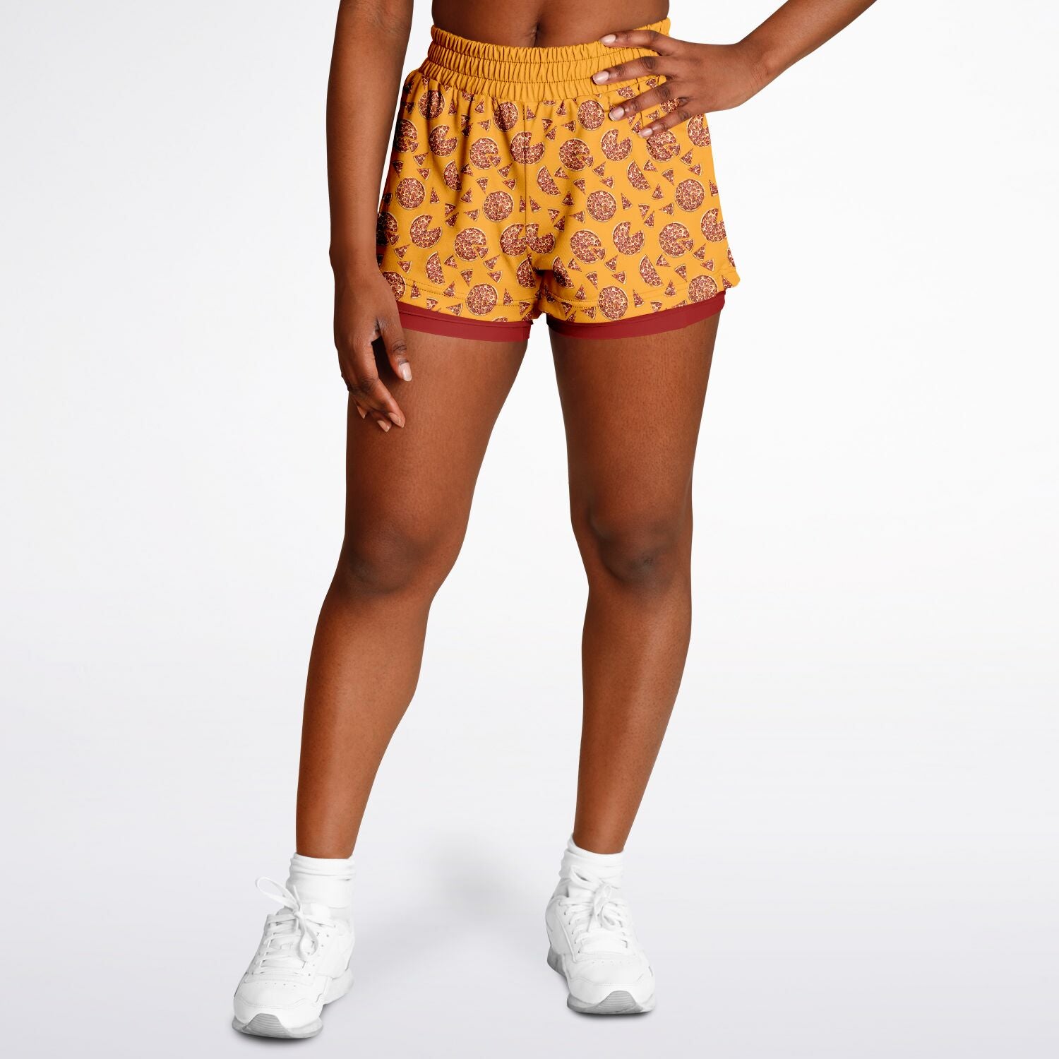 Women's shorts featuring a pizza design of pizza pies and pizza slices on a yellow background with a red under short.