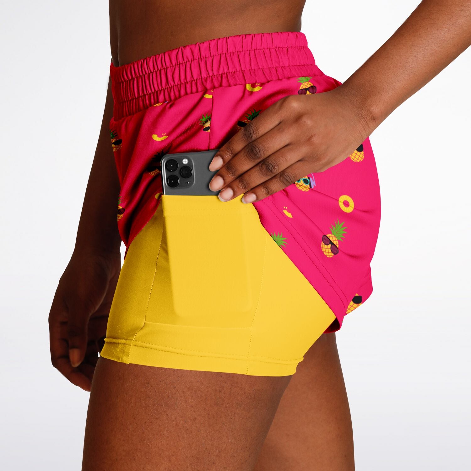 Women's 2-in-1 Shorts. These fun shorts feature a pink background with pineapples wearing a variety of sunglasses, and a yellow under-short with a hidden phone pocket.